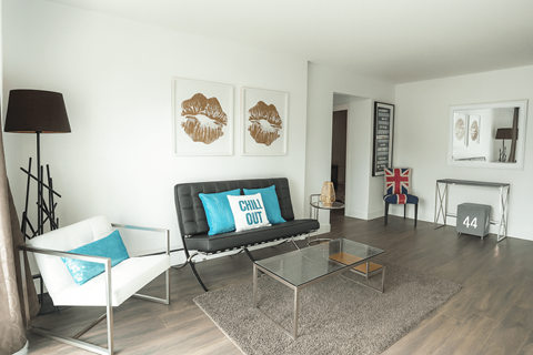 A living room with a black couch and a white chair.