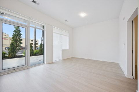 A spacious room with a sliding glass door and wooden flooring.