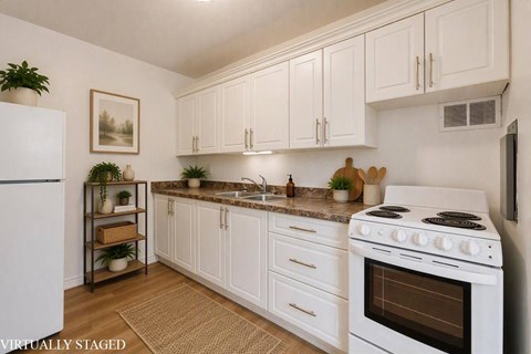 A kitchen with white cabinets and a white stove top oven.