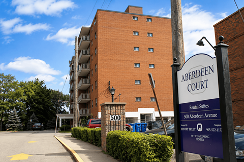 A sign for Aberdeen Court Rental Suites stands in front of a brick building.