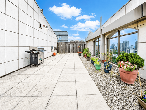 A rooftop patio with potted plants and a view of the city.