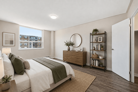 A bedroom with a large bed and a window overlooking a building.