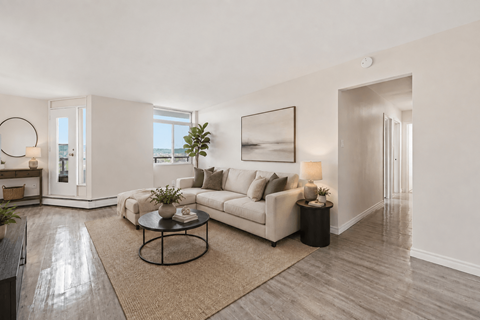 A living room with a white couch, a coffee table, and a large painting on the wall.