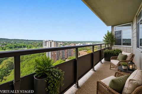 A balcony with a table and chairs overlooking a cityscape.