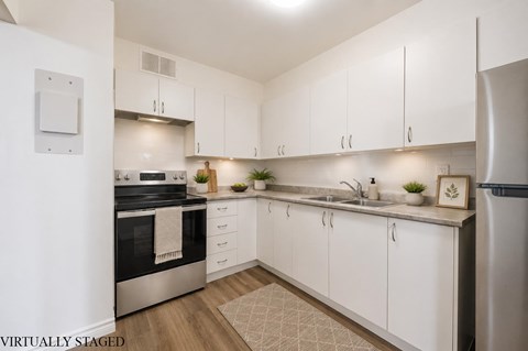 A kitchen with white cabinets and a stainless steel refrigerator.