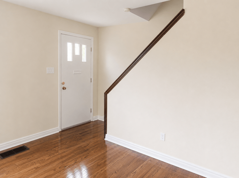 A white door is in a room with wooden floors and a staircase.