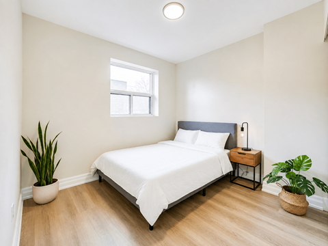 A bedroom with a white bed and a window.