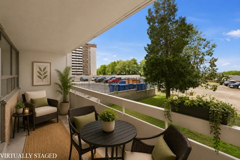 A balcony with a table and chairs overlooking a parking lot.
