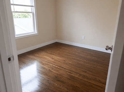 A room with wooden flooring and a window letting in natural light.