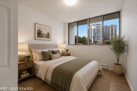 A bedroom with a large bed and a potted plant.