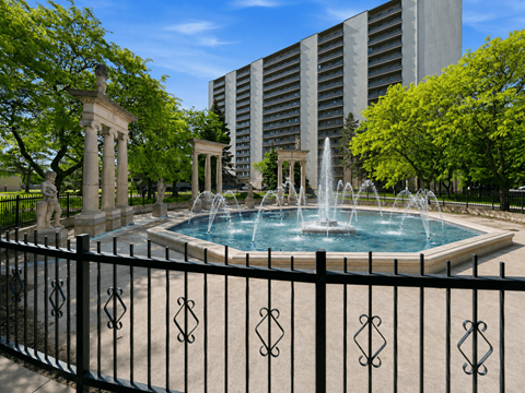 A fountain in the middle of a pool surrounded by a black fence.