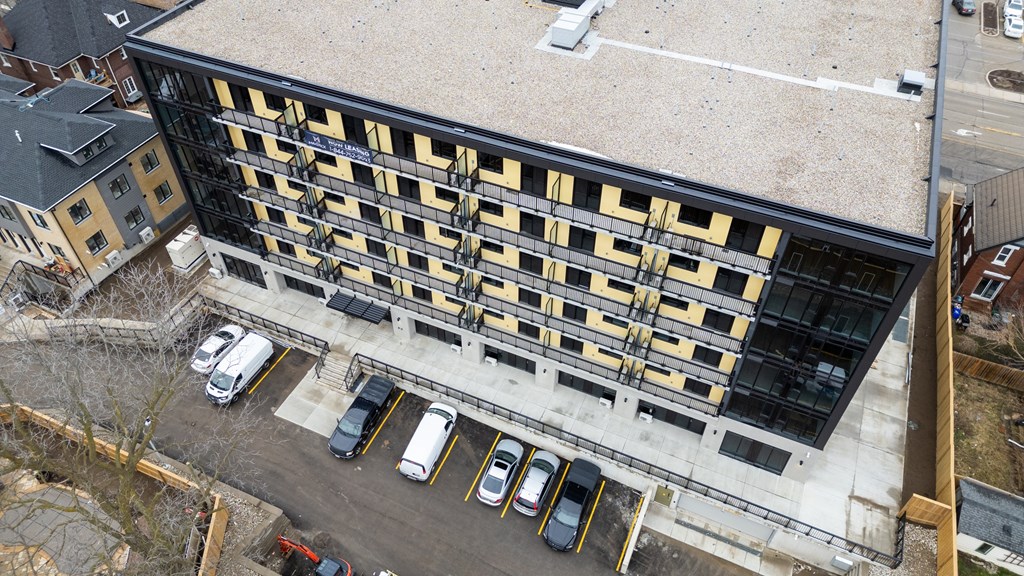 A parking lot with cars and a building with yellow and black stripes.