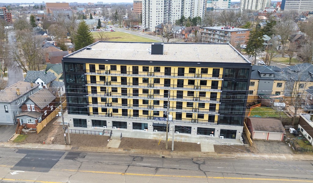 A large building with a black roof and yellow and black striped walls is under construction.