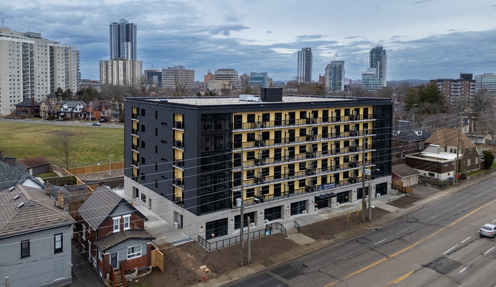 A modern building with a black and yellow facade is under construction in a suburban area.