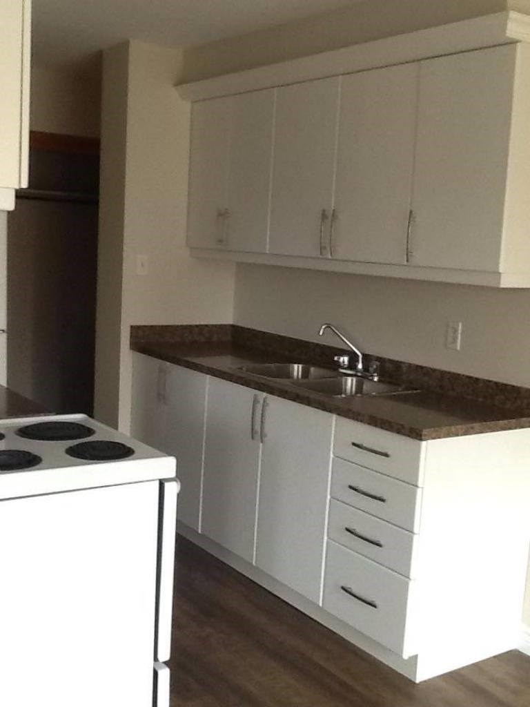 A kitchen with white cabinets and a white stove.