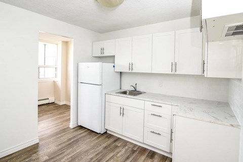 A kitchen with white cabinets and a marble countertop.