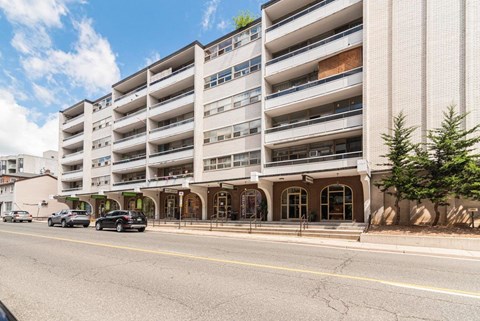 A large white building with a green sign on the top left corner.
