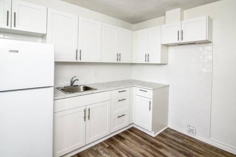 A kitchen with white cabinets and a white fridge.