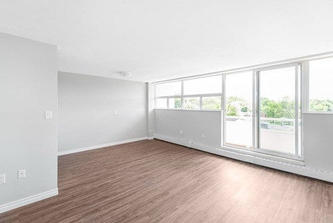 A room with wooden flooring and large windows.