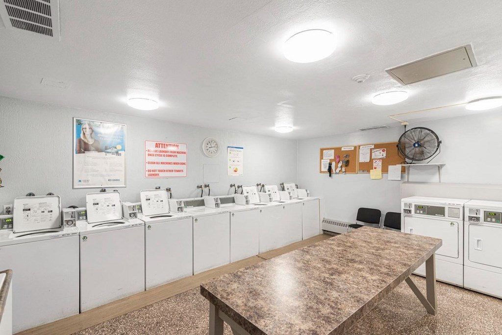 A laundromat with washers and dryers lined up on the wall.