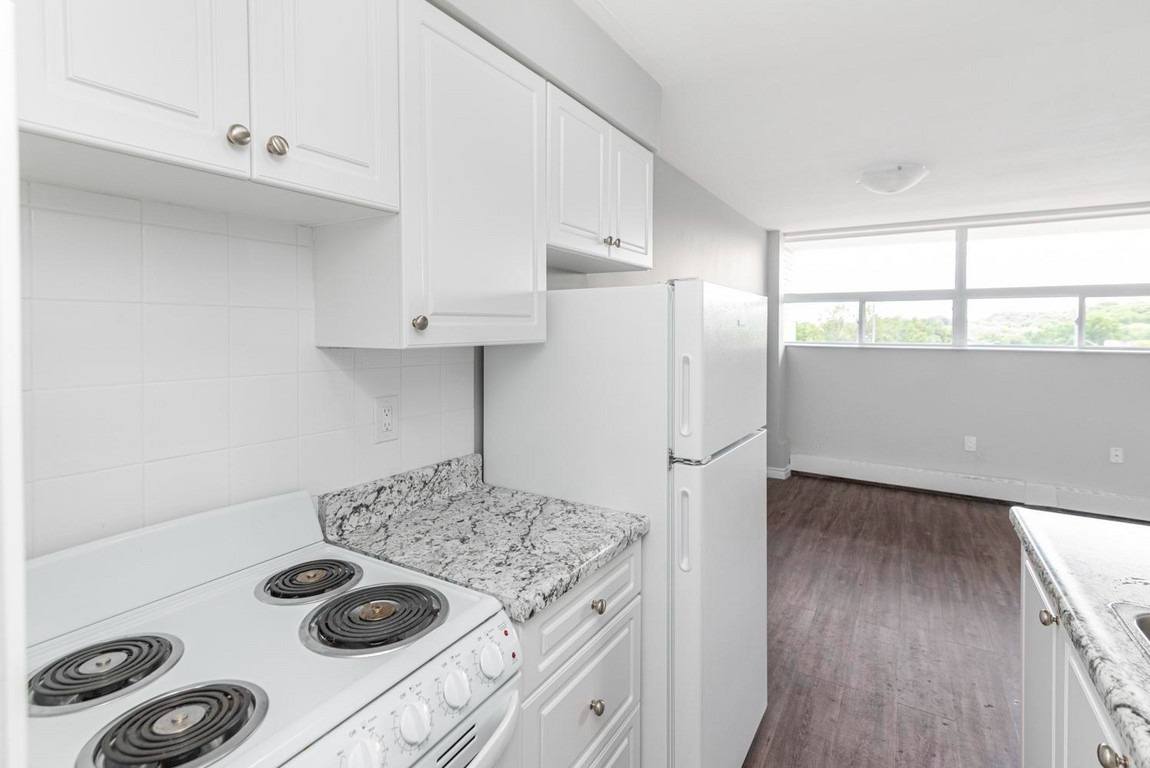 A kitchen with white cabinets and a granite countertop.