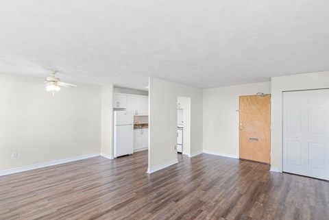A room with a white ceiling and wooden floors with a washing machine and dryer in the background.