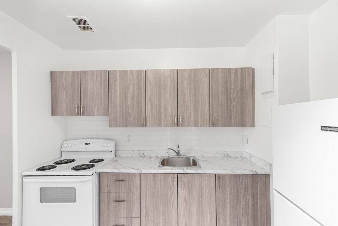 A kitchen with a white stove and wooden cabinets.