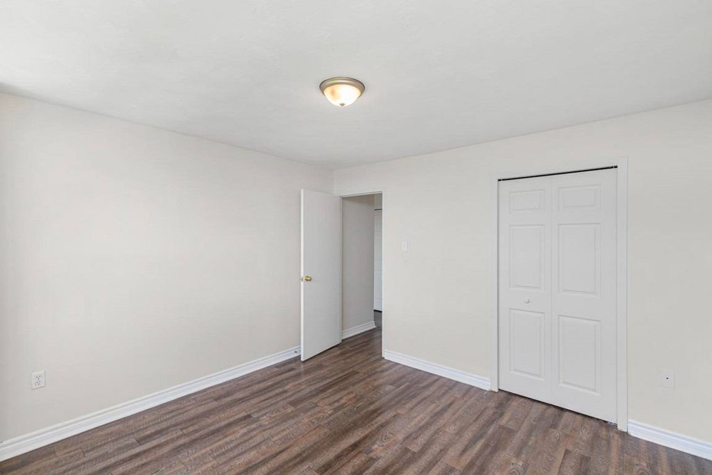 A room with a white door and a brown floor.