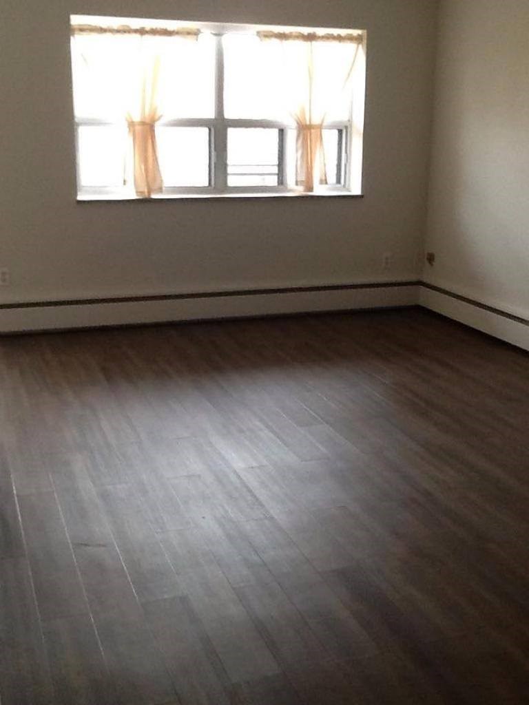 A room with a window and wooden flooring.