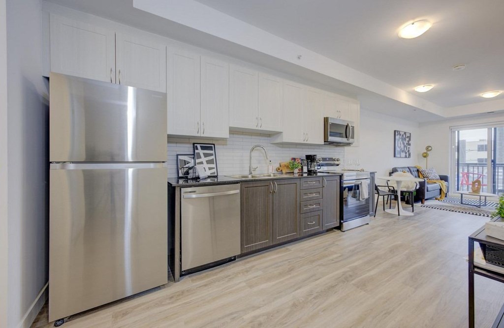 A modern kitchen with a stainless steel refrigerator and wooden flooring.at The Maverick, Kitchener, ON