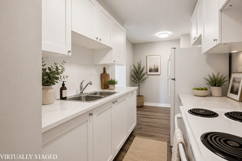 A kitchen with white cabinets and a stove top oven.