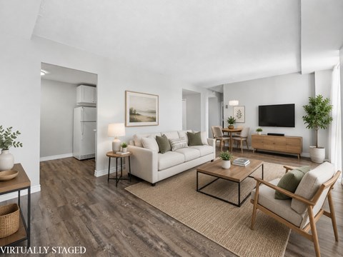 A living room with a white couch, a coffee table, and a television.