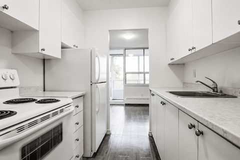 A white kitchen with a stove, refrigerator, and sink.