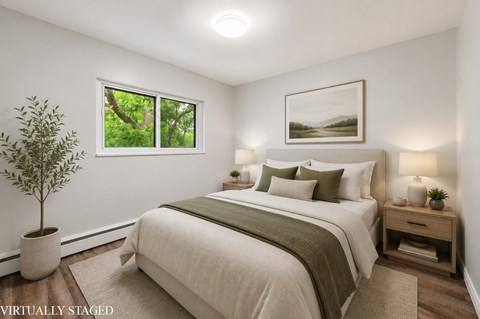 A bedroom with a large bed and a potted plant.