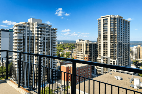 A balcony overlooks a cityscape with buildings and a clear blue sky.