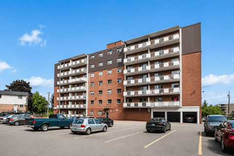 A large apartment building with a parking lot in front.