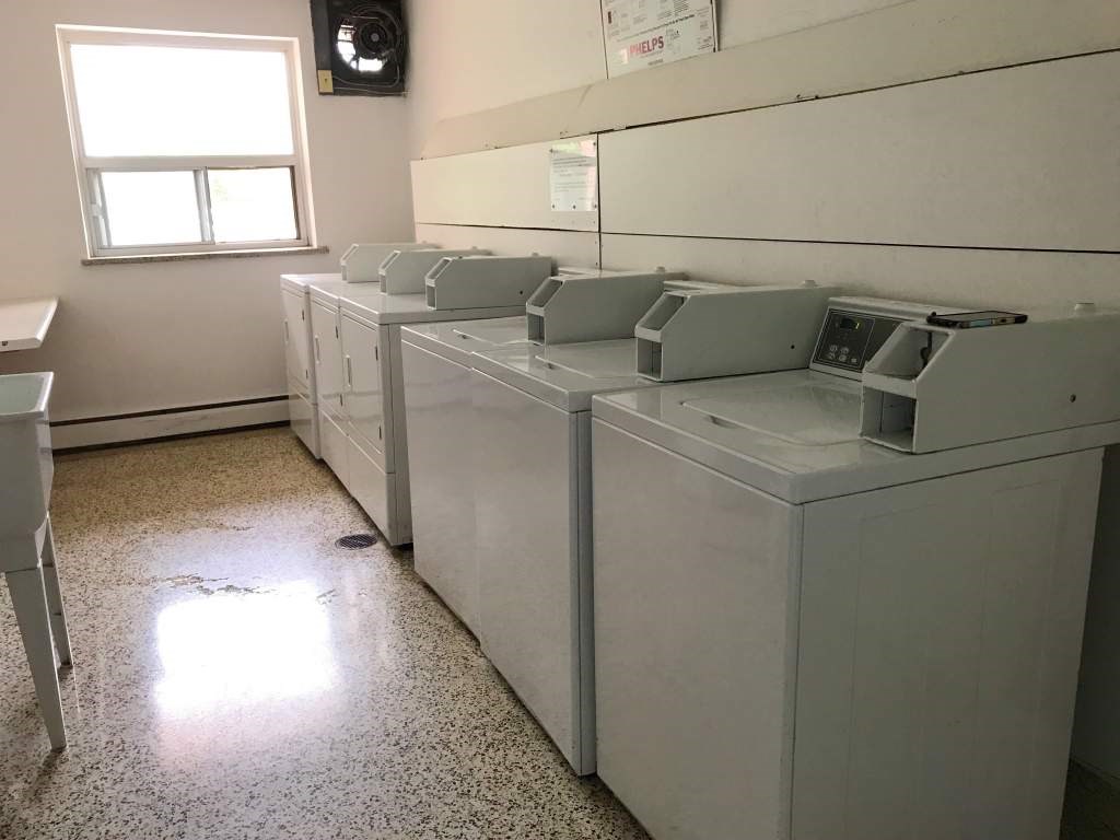 A room with a row of washing machines.