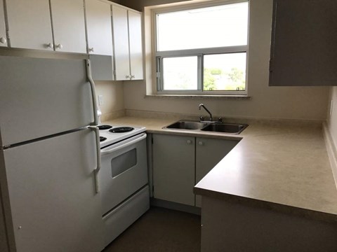A kitchen with white appliances and a window.