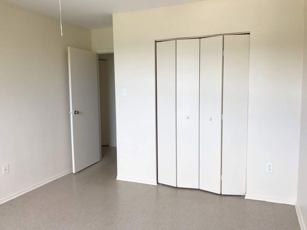A room with a white door and a white closet with four doors.