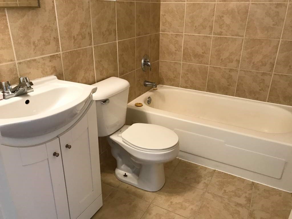 A white toilet sits next to a sink in a tiled bathroom.