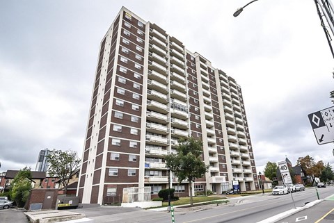 A tall apartment building with a parking lot in front.
