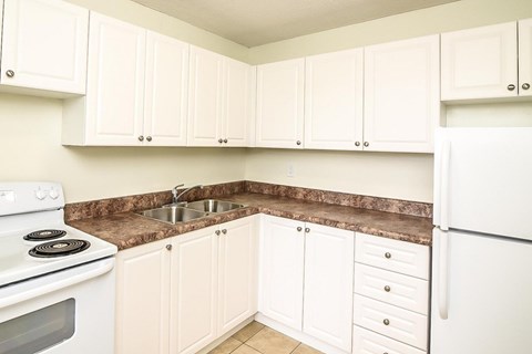 A kitchen with white cabinets and a white refrigerator.