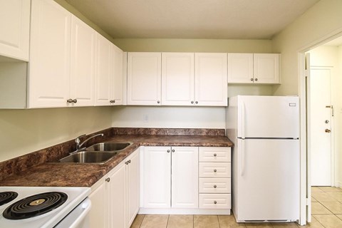 A kitchen with white cabinets and a white refrigerator.