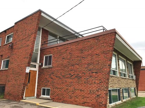 A red brick building with a brown door and windows.