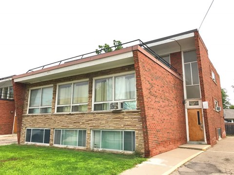 A red brick building with a balcony and a door.