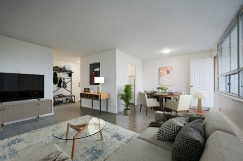 A living room with a grey couch and a glass coffee table.