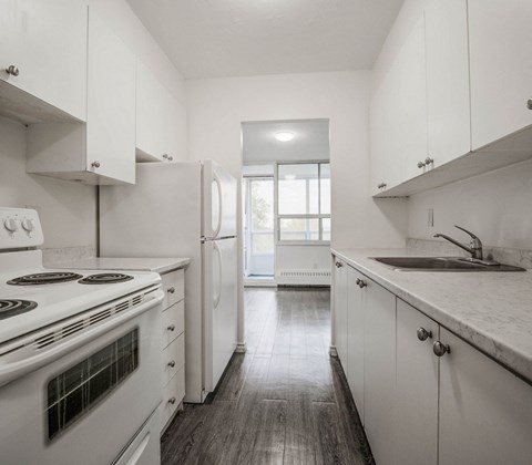 A kitchen with white cabinets and a stove top oven.