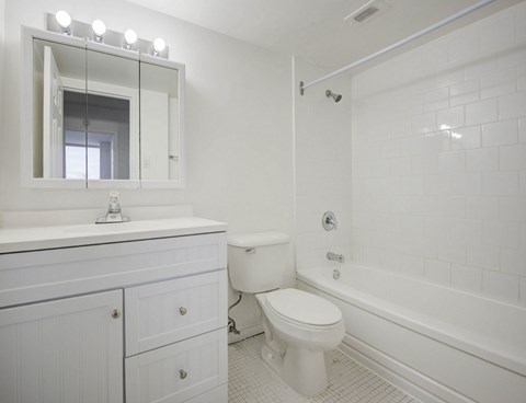 A white bathroom with a toilet, sink, and mirror.