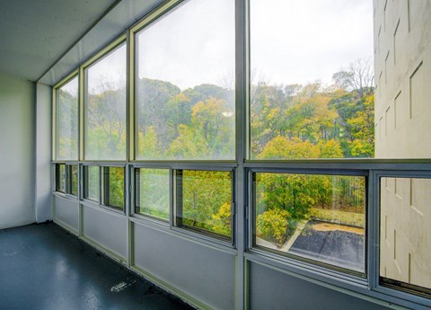 A room with large windows overlooking a tree-filled landscape.
