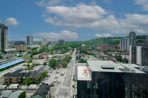A cityscape with buildings, roads, and cars under a partly cloudy sky.